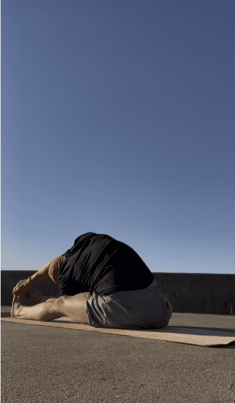 Frank Pineiro practising a seated forward fold outdoors