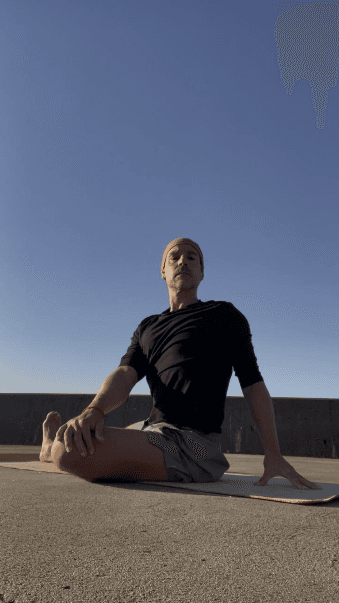 Frank Pineiro seated on a yoga mat during an outdoor practice